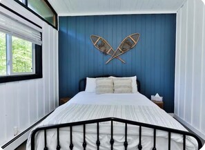 Un dormitorio con cama, ventana y pared azul.