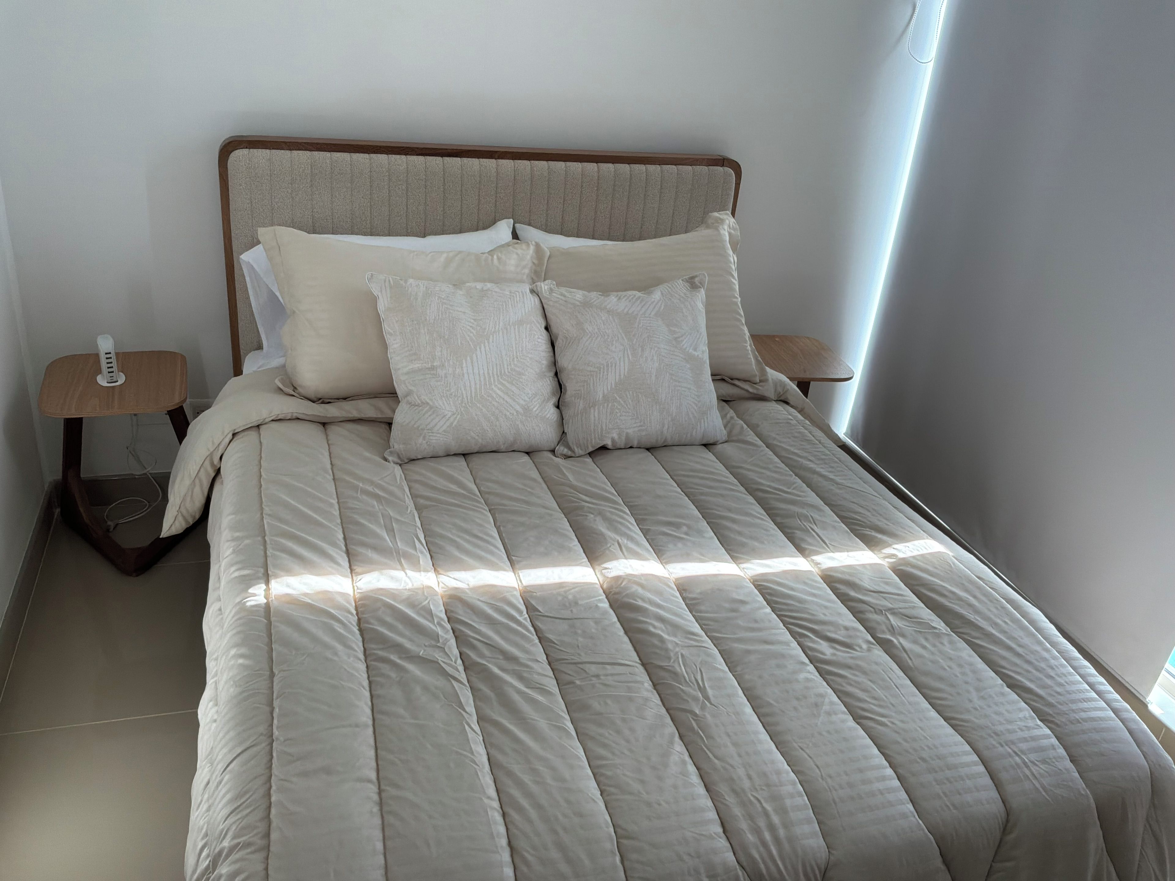 Un lit avec une tête de lit, deux tables de chevet et une lampe de chevet.