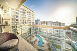 A high-rise building with a glass balcony overlooking a swimming pool and other buildings. - Cozy 2-bedroom apartment with Ocean View Reserva Del Mar 2 (Gaira)