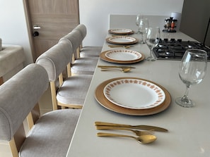 A dining table set with plates, cutlery, and glasses, with a kitchen area visible in the background. - Cozy 2-bedroom apartment with Ocean View Reserva Del Mar 2 (Gaira)