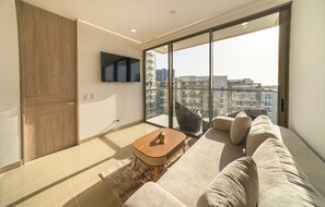 Ein modernes Wohnzimmer mit einer Couch, einem Couchtisch und einem an der Wand befestigten Fernseher.
