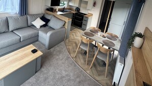 Een functionele woonruimte met een bank, eettafel en kitchenette.
