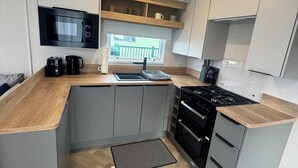 Een moderne keuken met grijze kastjes, een zwarte kookplaat en een magnetron boven het aanrecht.
