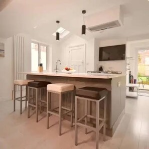 A modern kitchen with a central island, bar stools, a built-in oven, and a large window. - Sea-Renity Sidmouth Sleeps 6 Parking for 2 Vehicles (Sidmouth)