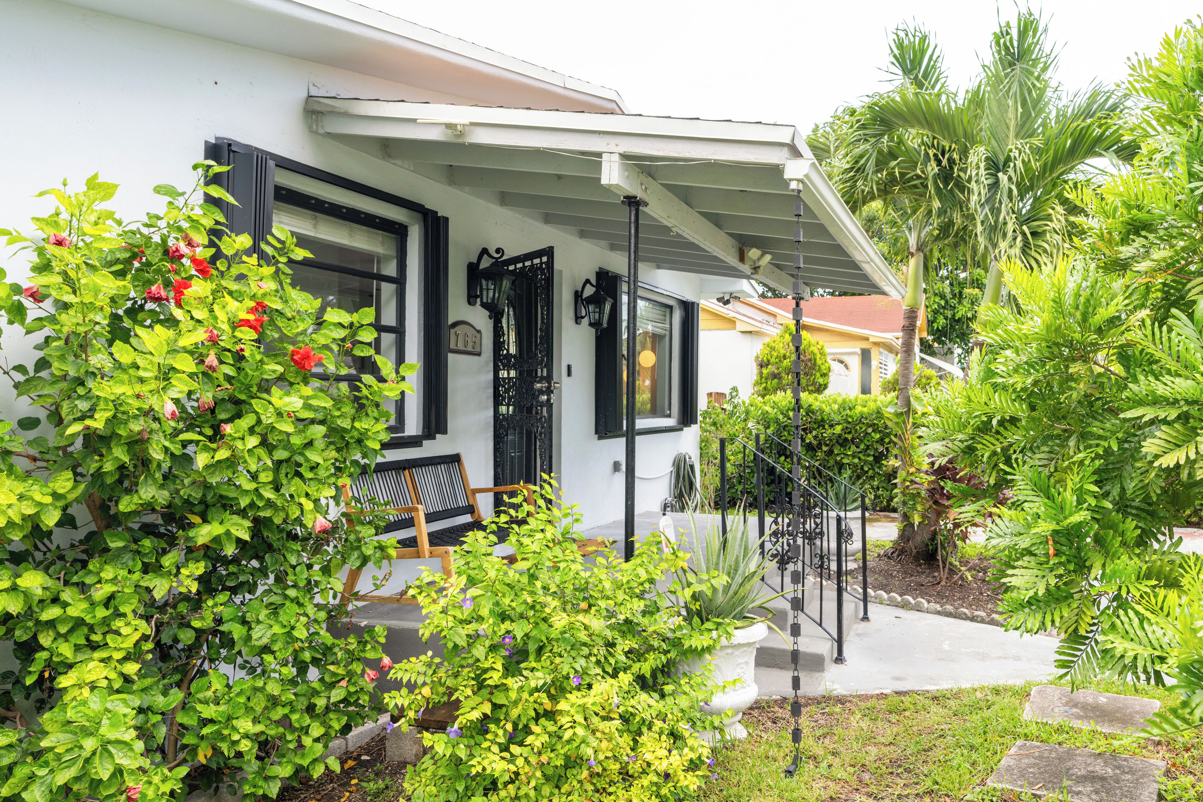 A house with a porch, a bench, and various plants.