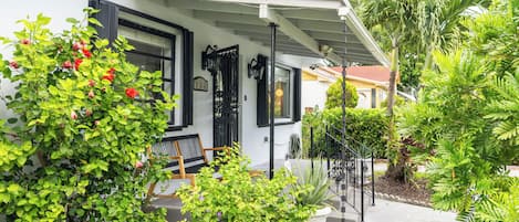 A house with a porch, a bench, and various plants.