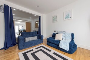 Ein modernes Wohnzimmer mit zwei Sofas, einem gemusterten Teppich und Bildern an den Wänden.