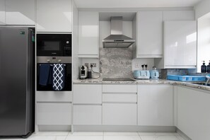 Eine moderne Küche mit weißen Schränken, einem Edelstahlkühlschrank, einem Bosch-Ofen und einer Mikrowelle.