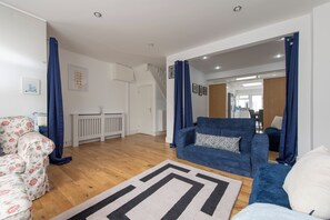 Ein modernes Wohnzimmer mit einer Couch, einem gemusterten Sessel und einem blauen Sofa.