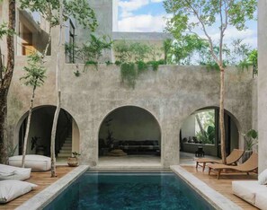 A pool area with three arched openings, wooden deck, and lounge chairs. - Casa Shalva with Chef & Transportation Included. Two Pools. (Tulum)