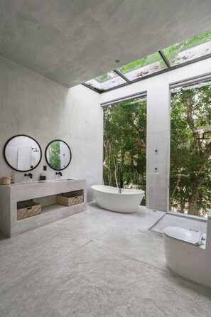 A modern bathroom with a freestanding bathtub, a double vanity with two mirrors, and a view of trees through large glass doors. - Casa Shalva with Chef & Transportation Included. Two Pools. (Tulum)