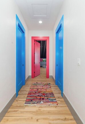 A hallway with blue doors, a colorful rug, and a white ceiling.