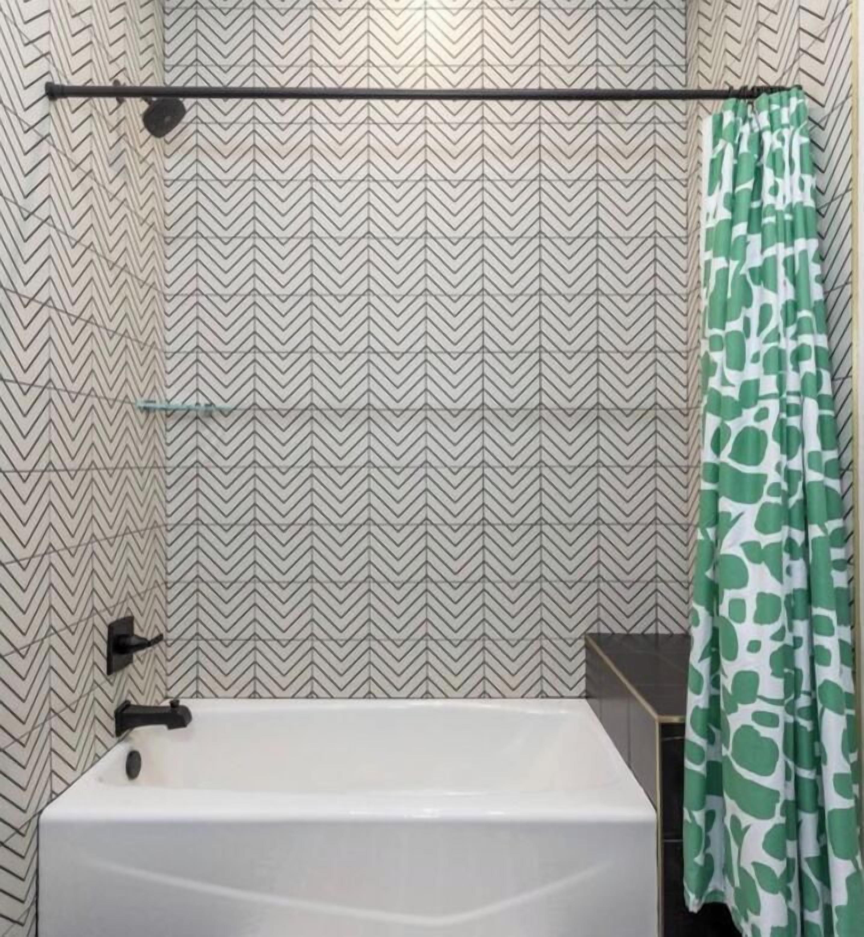 Ein Badezimmer mit einer weißen Badewanne, einer Duschvorhang und einer Wand mit Fischgrätmuster.