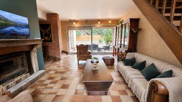A spacious living area with a fireplace, a sofa, a coffee table, and a television.