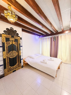 Ein Hotelzimmer mit einem Bett, Vorhängen, einer Zierhaustür und einer Deckenleuchte.