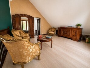 A spacious room with a high ceiling, a large mirror, ornate furniture, and a view of the outdoors.
