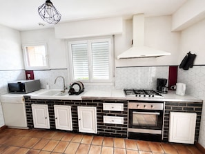A compact kitchen with a microwave, sink, stove, and oven.