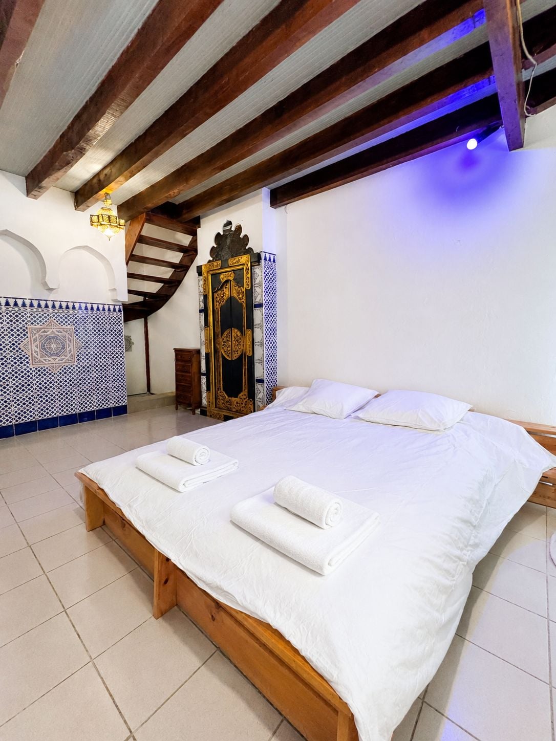 A hotel room with a large bed, wooden headboard, and a decorative gate.