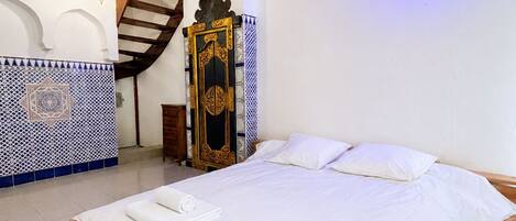 A hotel room with a large bed, wooden headboard, and a decorative gate.