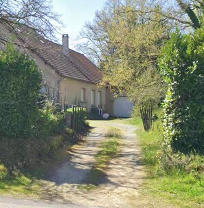 Ein ländliches Haus mit einer Schotterauffahrt, die zu einem Tor führt.