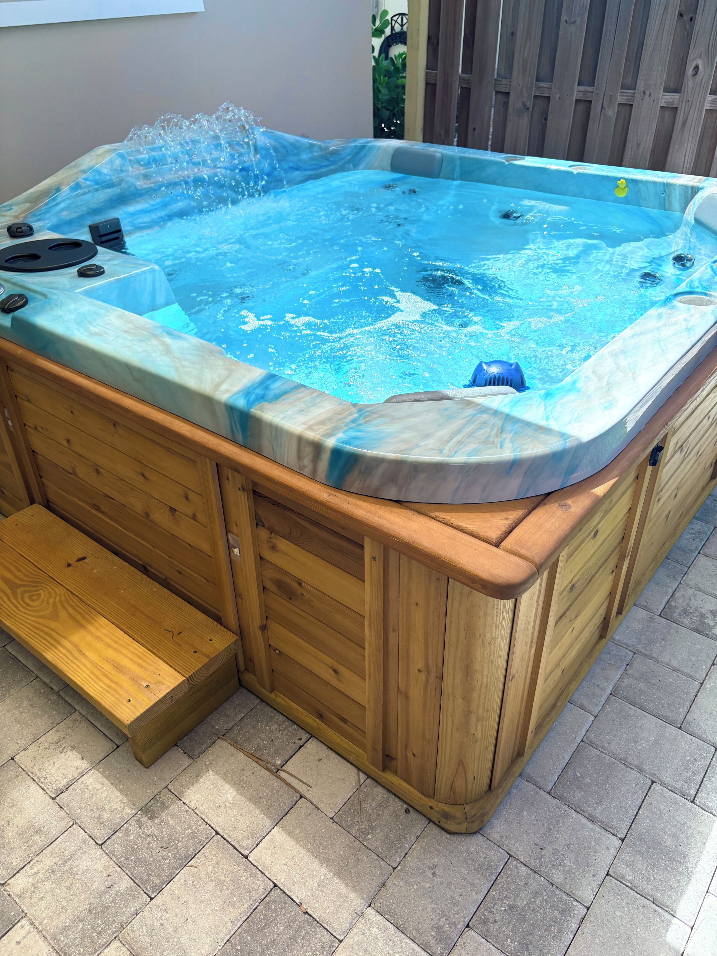 A hot tub with a wooden exterior, built-in seating, and a step for access.
