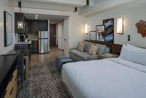 Una habitación de hotel con una cama, un sofá, un escritorio y una kitchenette.