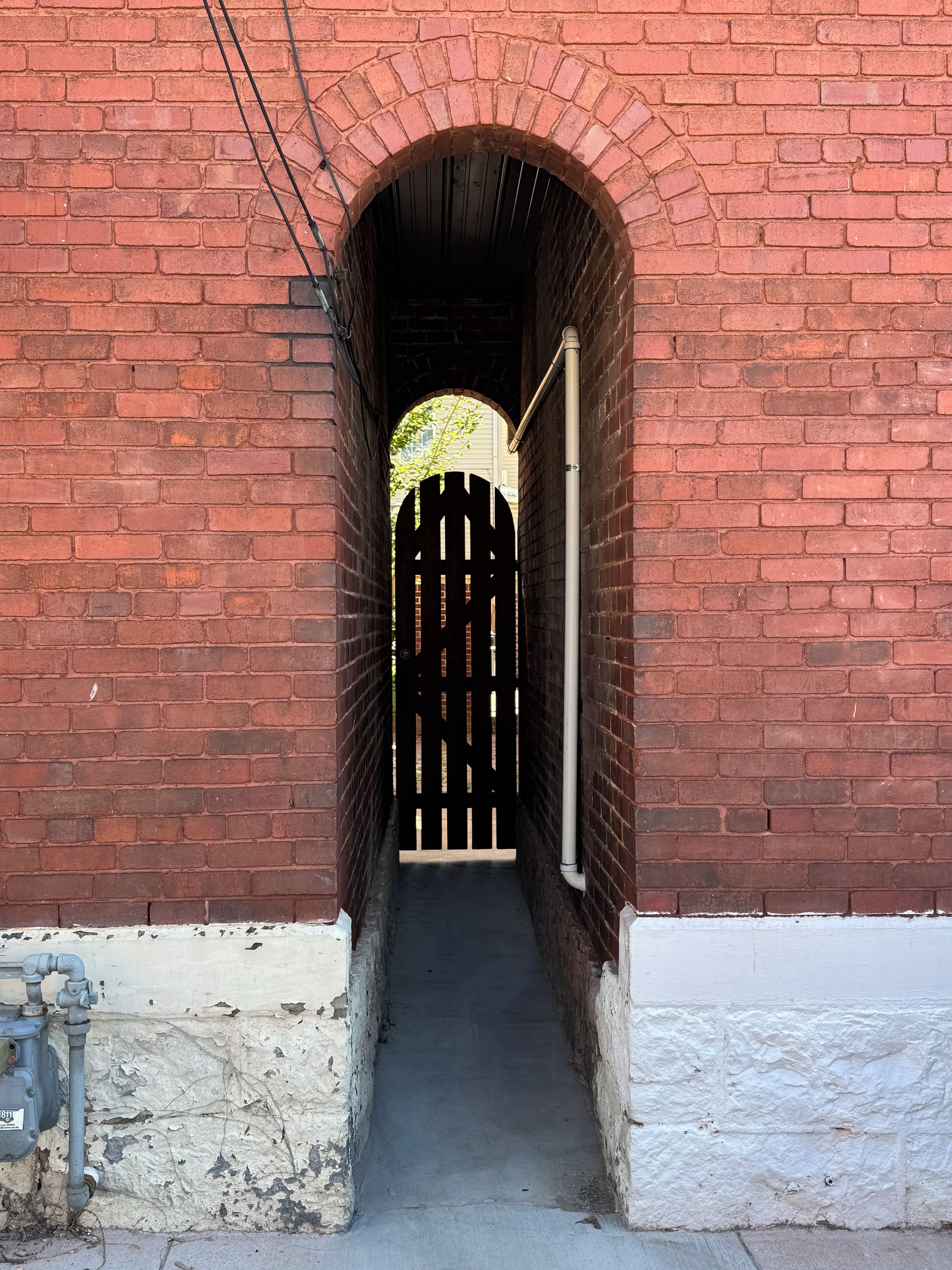 A brick tunnel with a wooden gate at the end.