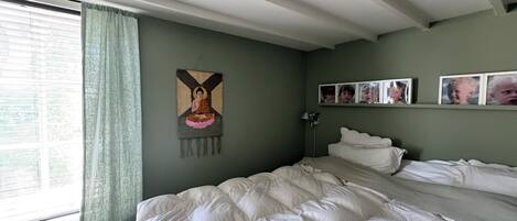 A bedroom with a bed, a wall-mounted picture, and a window with curtains.