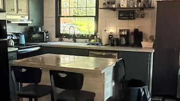A kitchen with a central island, bar stools, a window with a view, and a microwave.