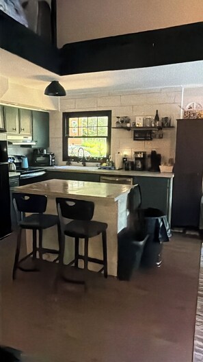 A kitchen with a central island, bar stools, a window with a view, and a microwave.