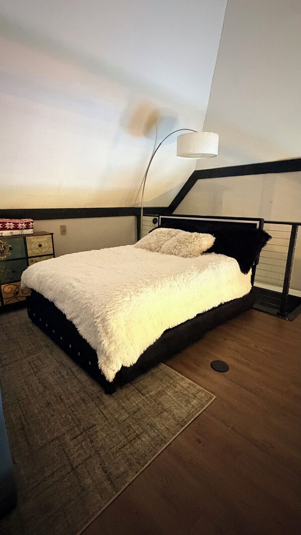 A bedroom with a bed, a nightstand, a lamp, and a dresser.