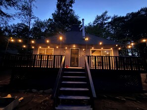 A small house with a porch, a staircase leading to the entrance, and string lights.