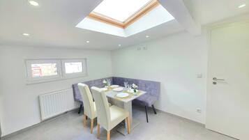A modern dining area with a skylight, a dining table set for four, and a bench.