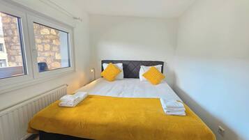 A hotel room with a bed, two windows, and a radiator.