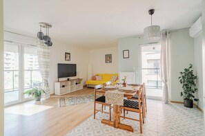 Ein modernes Wohnzimmer mit einer Couch, einem Esstisch und einem Fernseher.