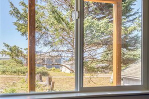 Vista da janela de uma área residencial com casas, árvores e céu claro.