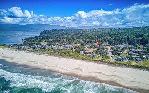 Uma área residencial à beira-mar, com casas, uma praia e uma colina arborizada.