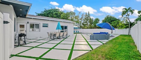 Un patio trasero con terraza, mobiliario exterior y un espacio cubierto.