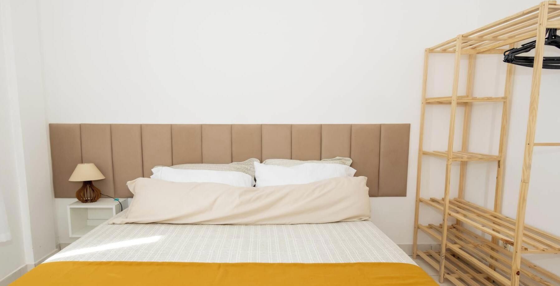 Un lit avec une tête de lit, une table de chevet avec une lampe et un porte-revues en bois.