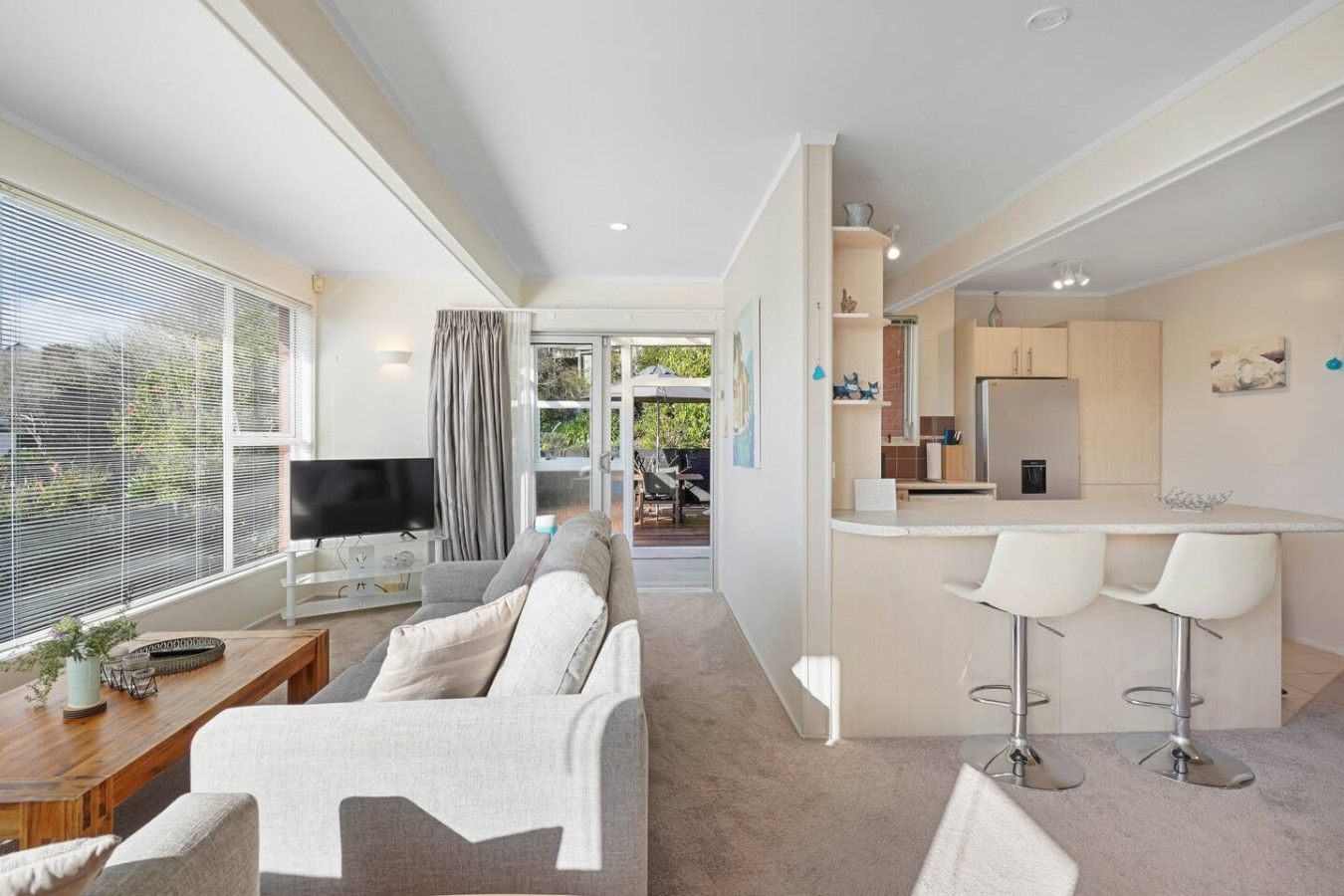 A modern living room with a sofa, TV, and a dining area with a bar.