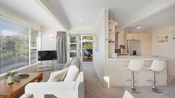 A modern living room with a sofa, TV, and a dining area with a bar.