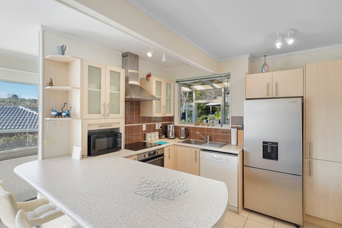 A modern kitchen with a large island, built-in appliances, and a view of the outdoors.