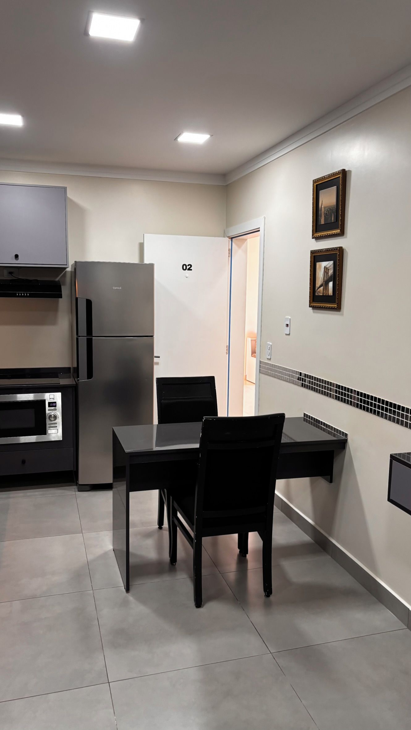 Cozinha moderna com geladeira, fogão e mesa de jantar com cadeiras.