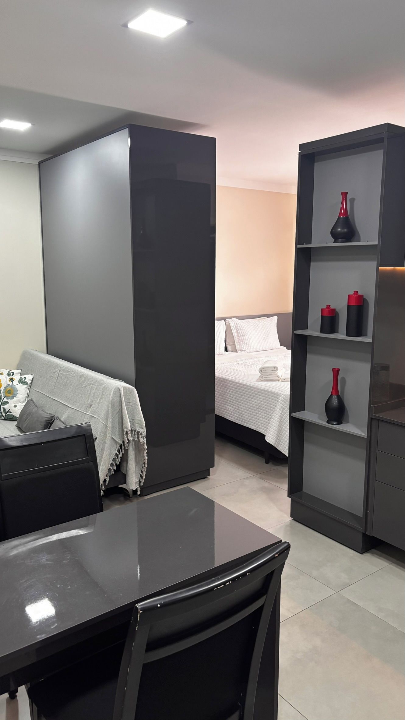 Quarto de hotel moderno com cama, escrivaninha e estante.