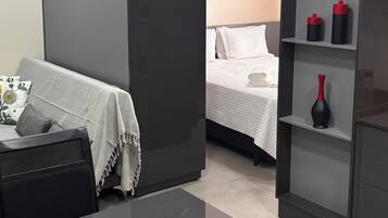Quarto de hotel moderno com cama, escrivaninha e estante.
