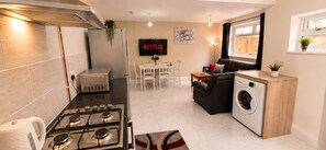 A compact kitchen with a gas stove, a microwave, and a washing machine. - Cathays 6BR House with Garden, Cardiff (Cardiff)