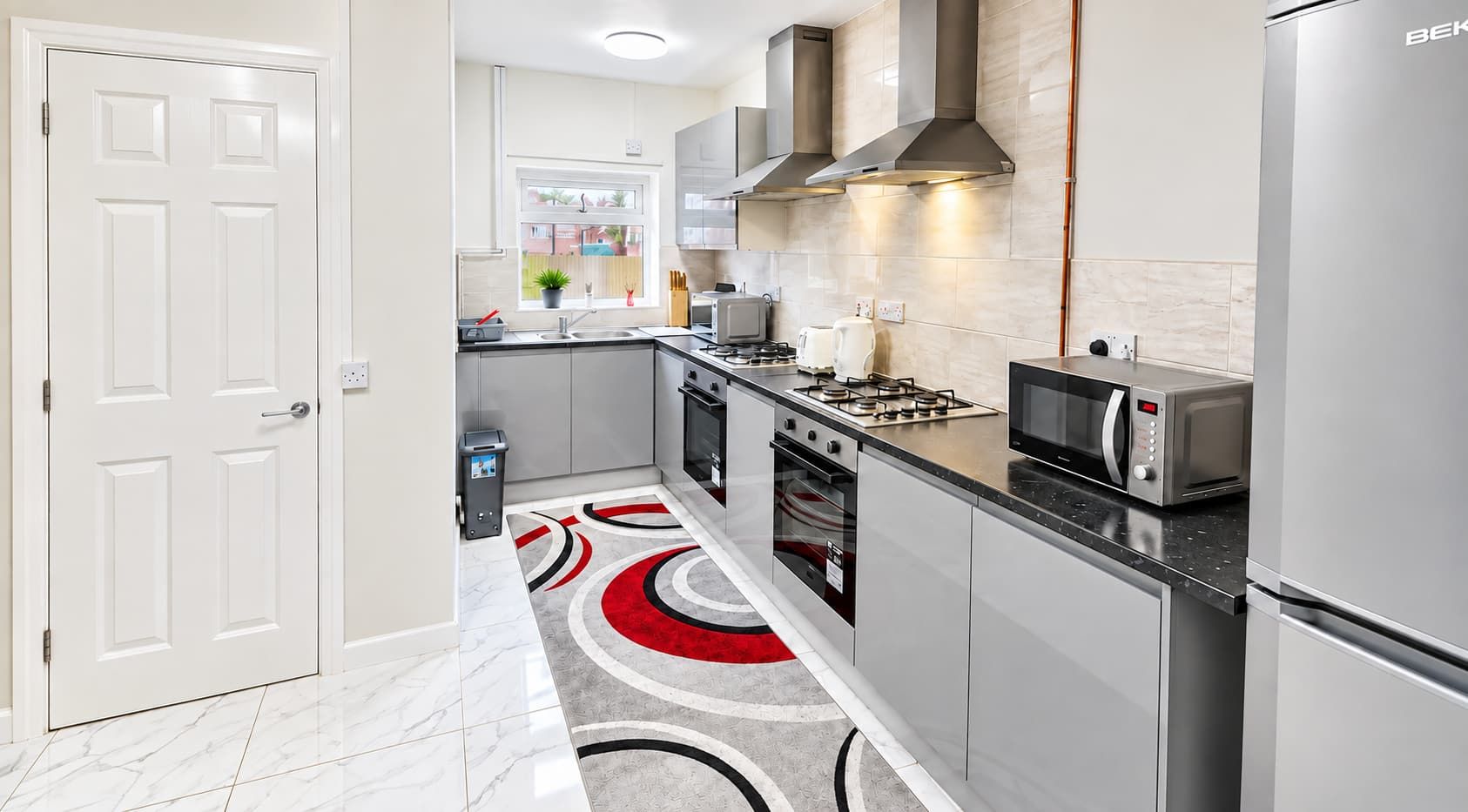 A modern kitchen with stainless steel appliances, a gas stove, and a microwave.