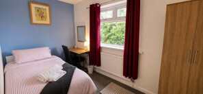 A bedroom with a bed, a desk, a chair, a wardrobe, and a window with curtains. - Cathays 6BR House with Garden, Cardiff (Cardiff)