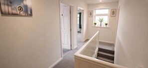 A hallway with a carpeted staircase, a door labeled '5', and a window with plants. - Cathays 6BR House with Garden, Cardiff (Cardiff)