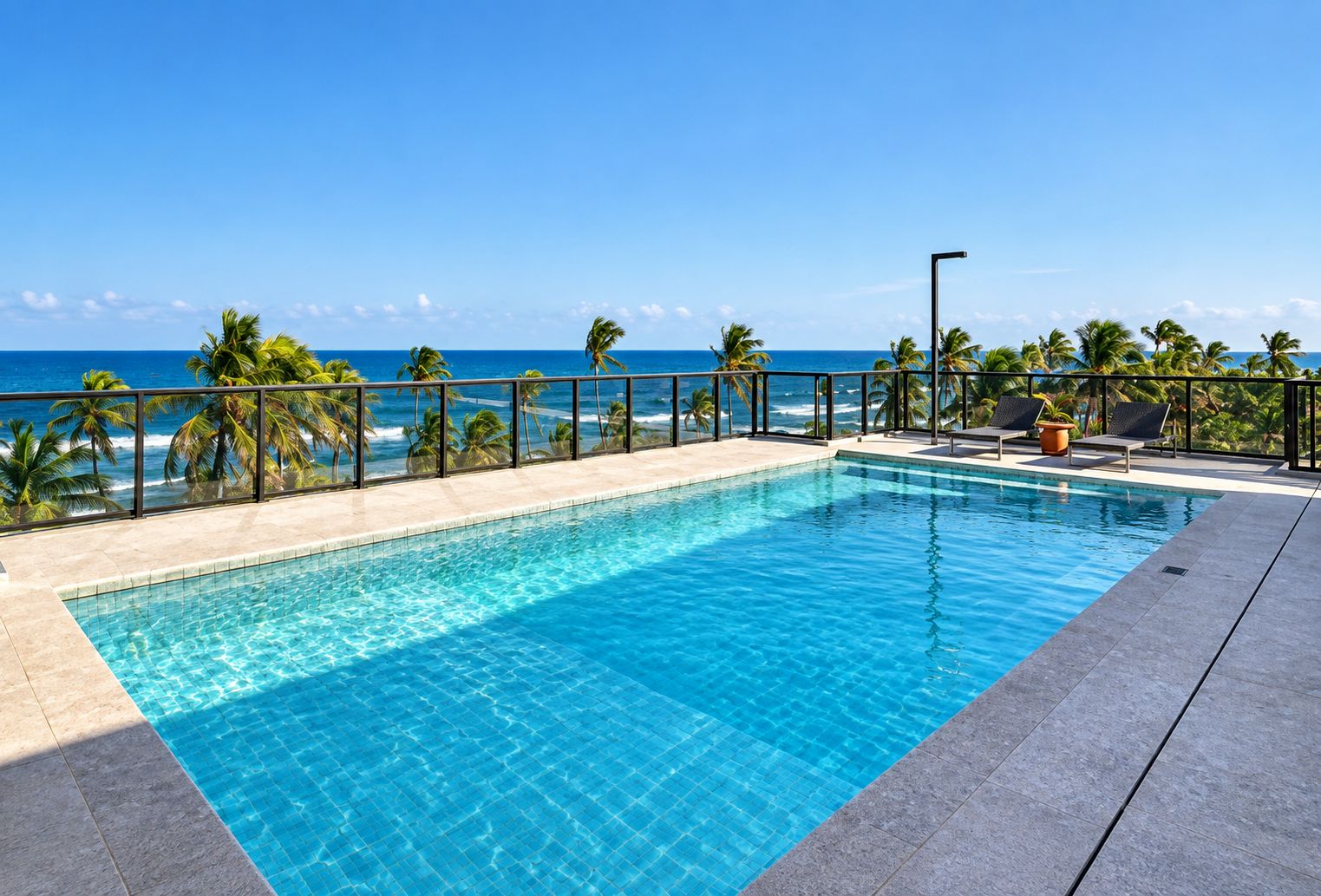 A rectangular pool with clear blue water, surrounded by a tiled deck and a railing.